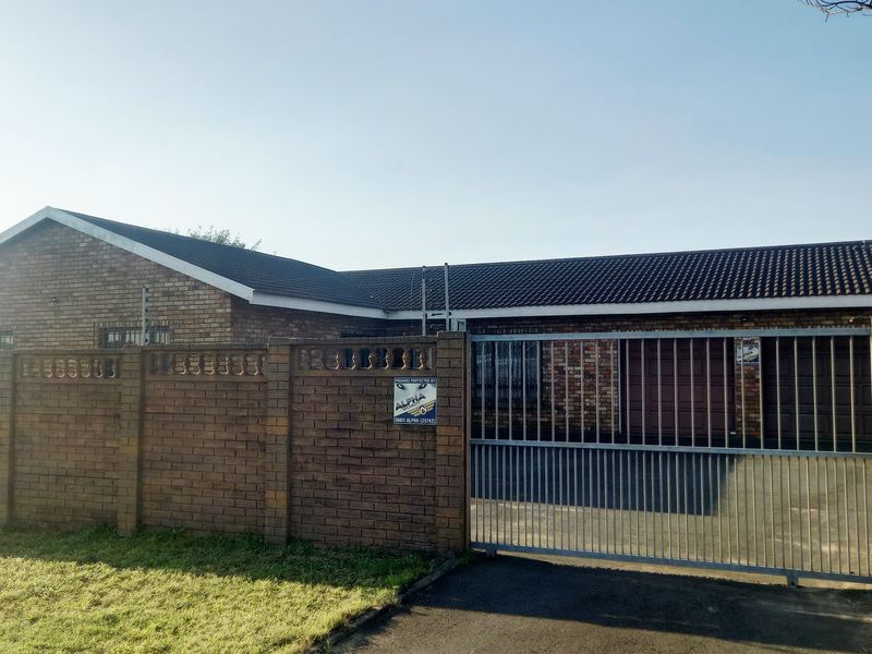 Front exterior view of a face brick house featuring a tiled roof, paved driveway, and a secure sliding gate with perimeter electric fencing.
