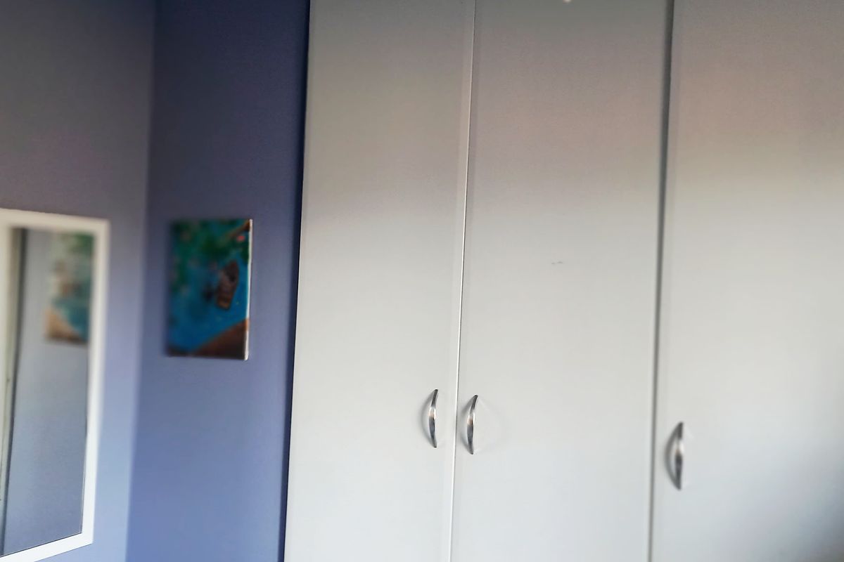 A bedroom featuring a built-in wardrobe with white doors and blue accent wall paint.