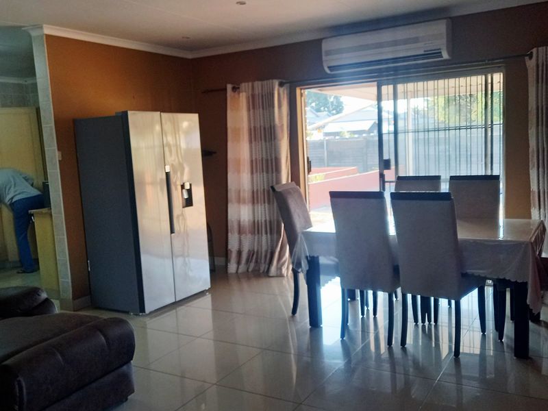 Open-plan living and dining area featuring tiled flooring, a split-system air conditioner, and direct access to the outdoor patio through sliding glass doors.