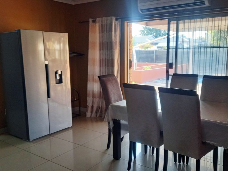 Dining area featuring tiled flooring, a wall-mounted air conditioning unit, and large sliding glass doors providing access to the outdoor patio area.