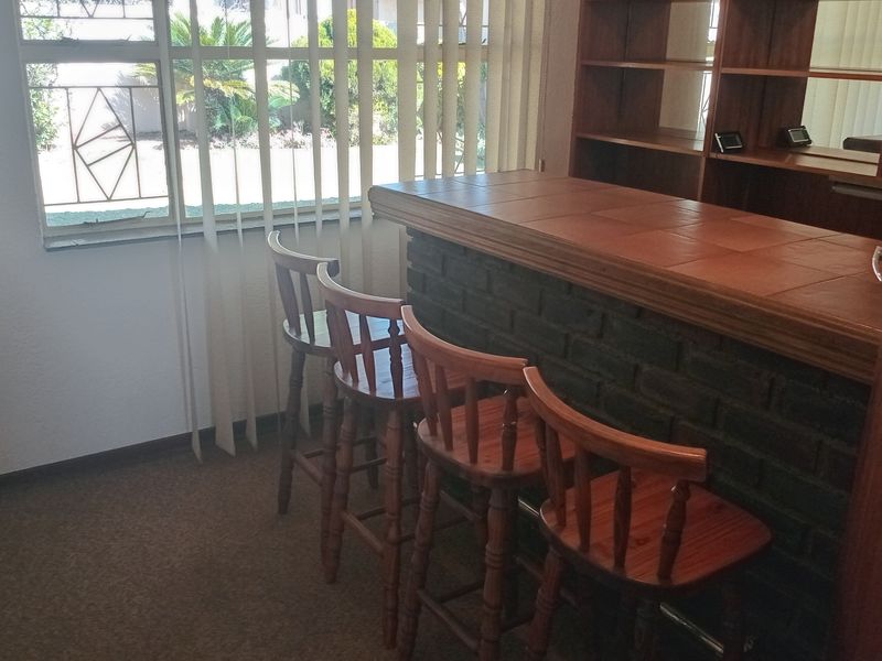 A dedicated bar area featuring a built-in brick base counter with a tiled top and integrated wooden shelving.