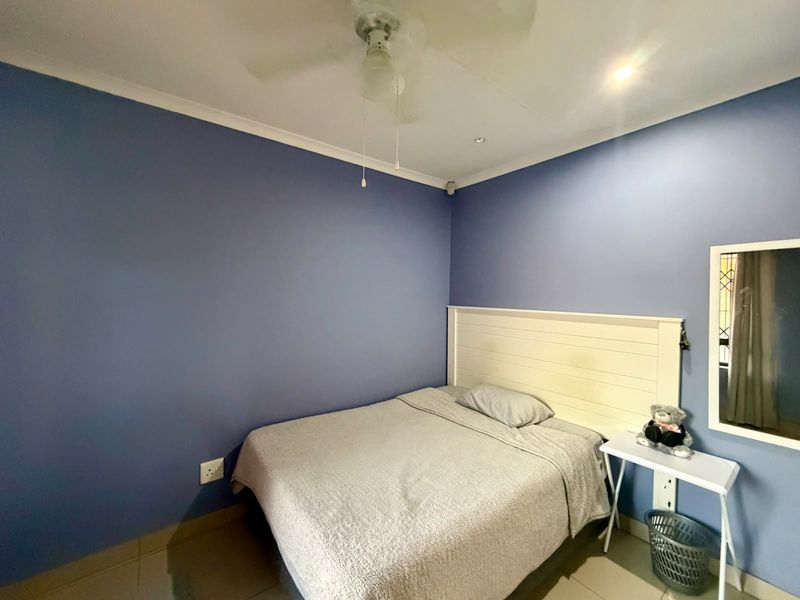 A bedroom featuring blue painted walls, tiled flooring, a ceiling fan, and a built-in headboard.