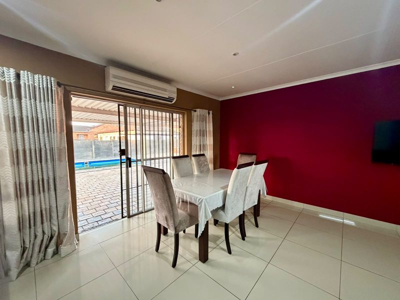 Dining room featuring tiled flooring, a split-system air conditioner, and a sliding door providing direct access to the outdoor patio and pool area.