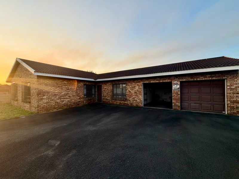 A single-story face brick house featuring a tiled roof, asphalt driveway, and an integrated garage with security bars on the windows.