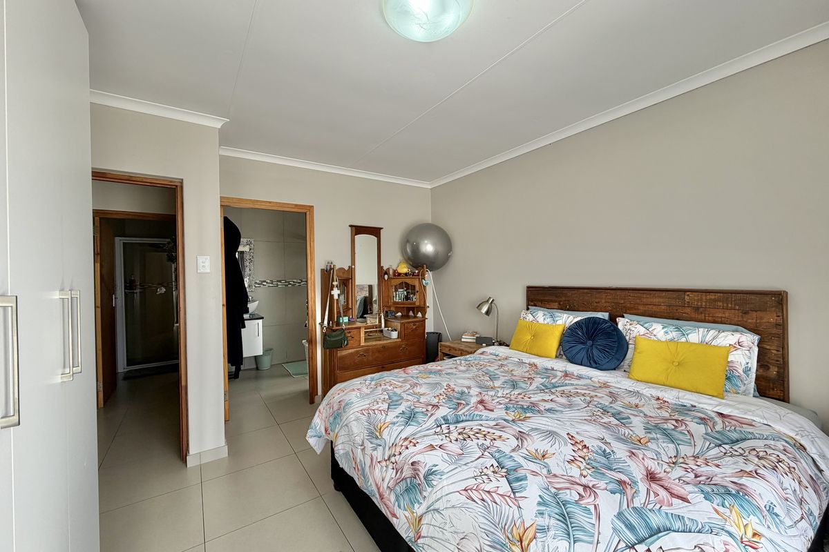 Spacious bedroom featuring neutral tiled flooring, built-in wardrobe storage, and direct access to an en-suite bathroom.