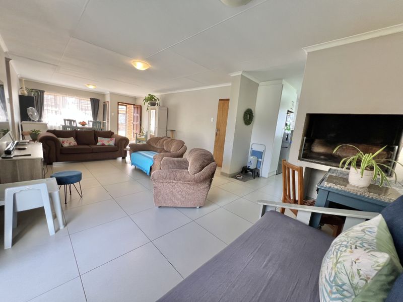Spacious open-plan living area featuring large floor tiles, a built-in fireplace, and direct access to the exterior, offering a versatile layout for family living.