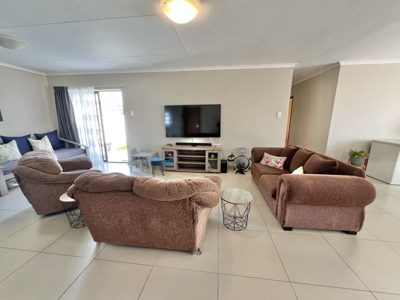 Spacious living room featuring neutral tiled flooring, coved ceilings, and a sliding glass door providing access to the outdoor area.