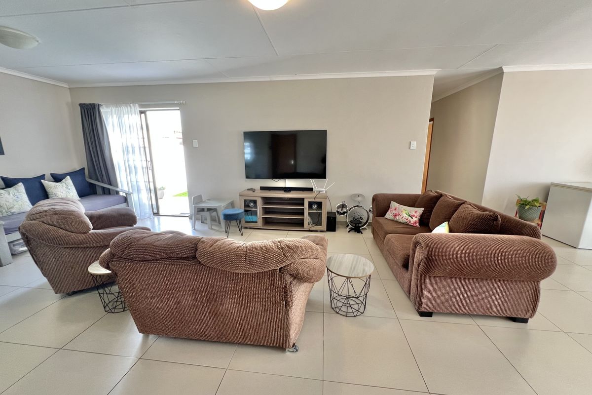 Spacious living room featuring neutral tiled flooring, coved ceilings, and a sliding glass door providing access to the outdoor area.