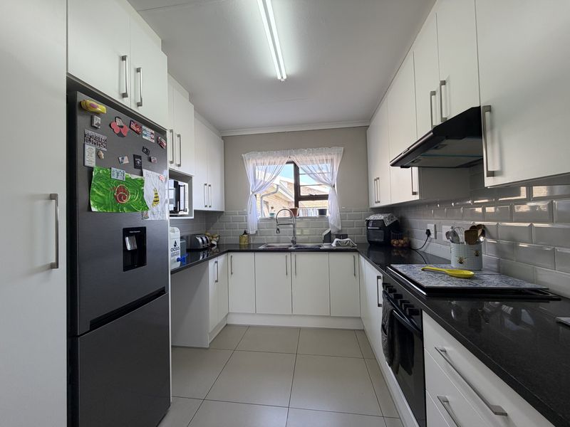 A well-maintained kitchen featuring white cabinetry, dark granite countertops, subway tile backsplash, and integrated appliances including an oven and extractor fan.