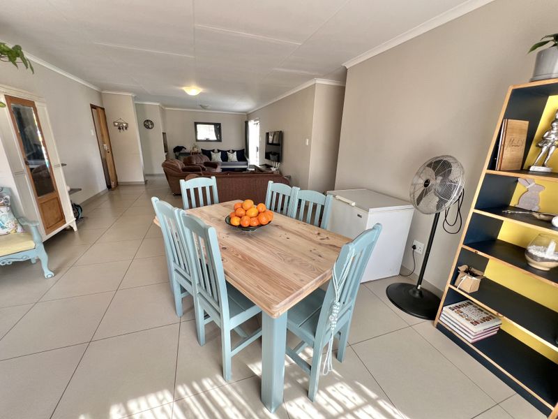 Spacious open-plan living and dining area featuring neutral wall tones and large format floor tiles throughout the main living space.
