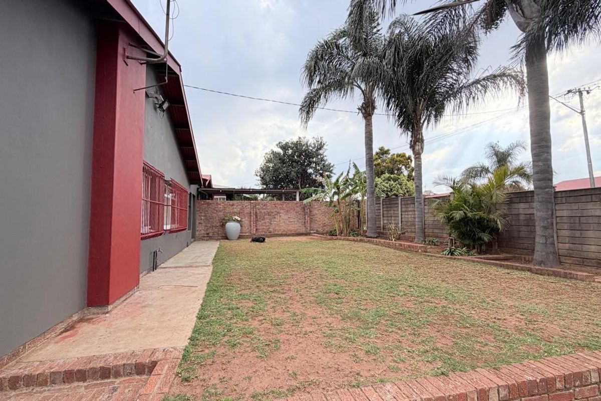 A rear garden area featuring a lawn, concrete walkway, and brick boundary walls, providing a private outdoor space.