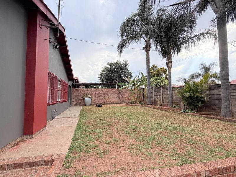 A rear garden area featuring a lawn, concrete walkway, and brick boundary walls, providing a private outdoor space.