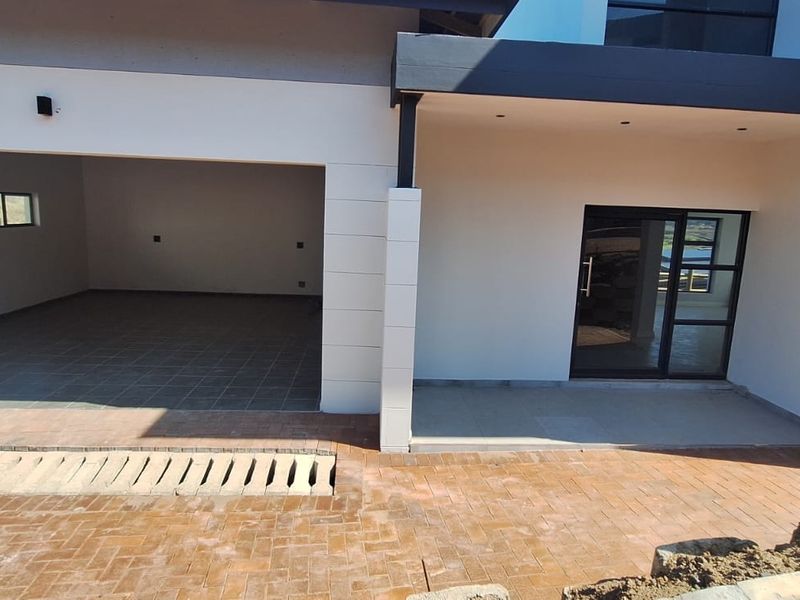 Modern front facade featuring a double garage with tiled flooring, a covered entrance, and a paved driveway area.