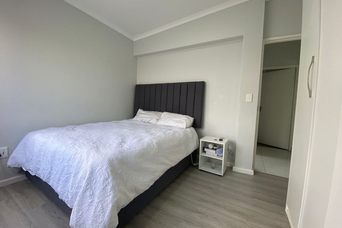 A well-maintained bedroom featuring modern laminate flooring, neutral wall tones, and a built-in wardrobe, offering a clean and functional living space.