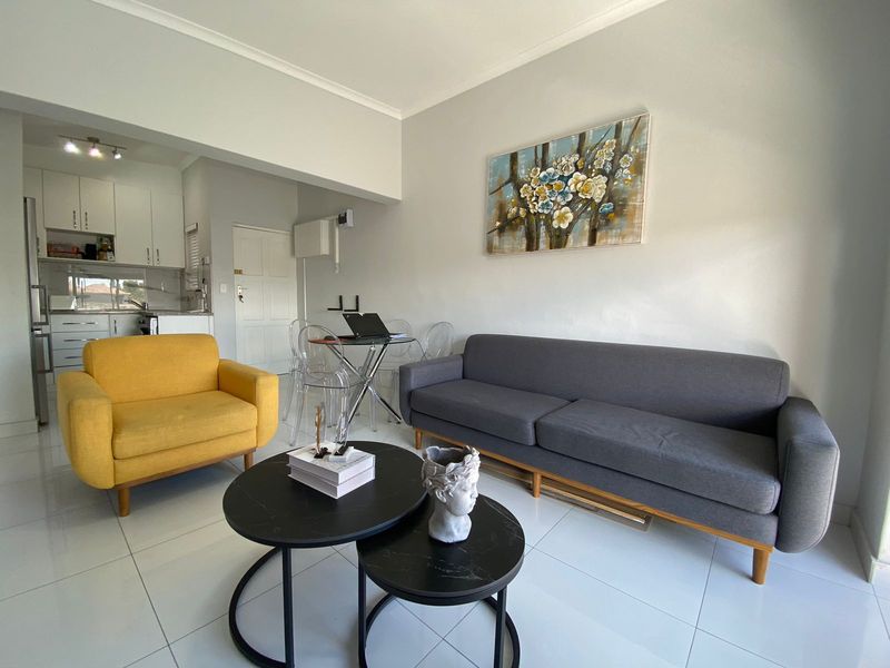 Open-plan living area featuring tiled flooring and a modern kitchen with built-in cabinetry, creating a bright and functional space.