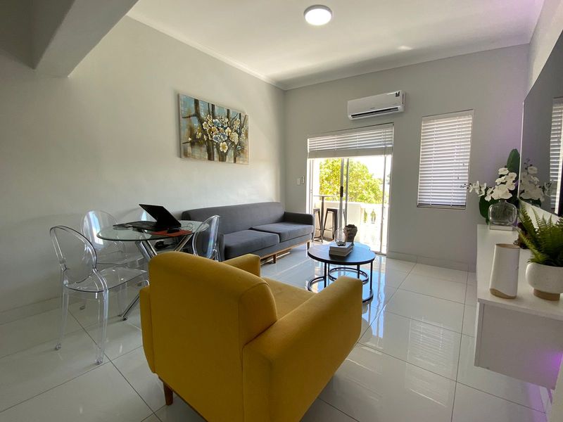 A bright and modern living room featuring polished tiled flooring, an integrated air conditioning unit, and sliding glass doors leading to an outdoor area.