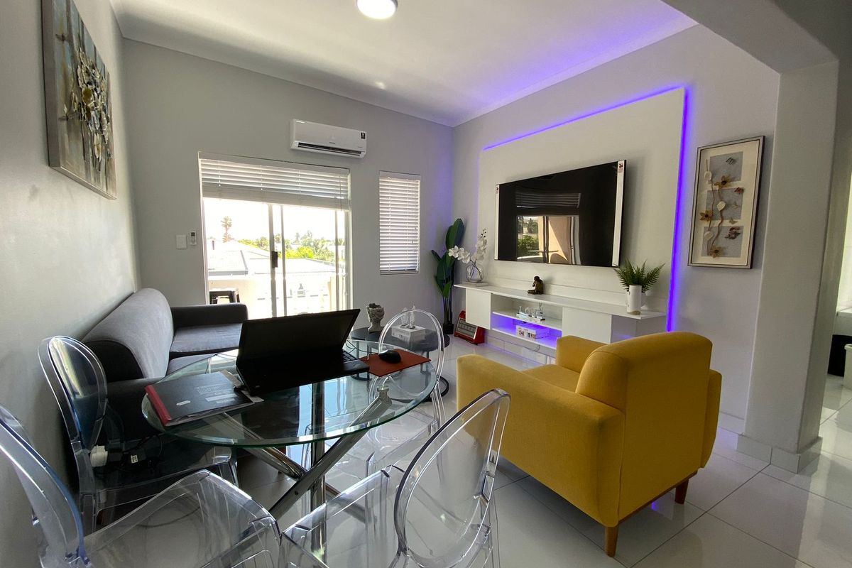 Modern living room featuring tiled flooring, a built-in media console with integrated LED lighting, and a split-system air conditioner with access to a balcony.