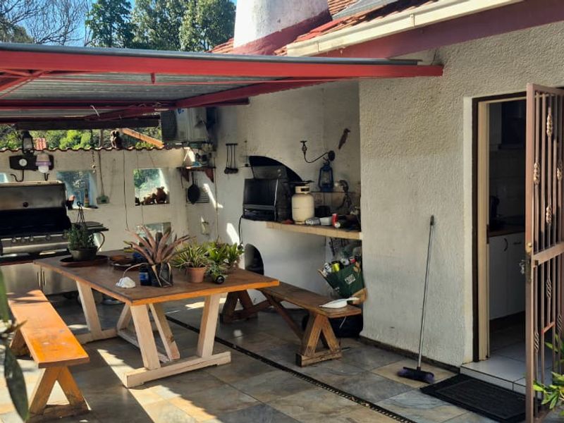 Covered outdoor patio area featuring a built-in braai, tiled flooring, and direct access to the home through a security gate.