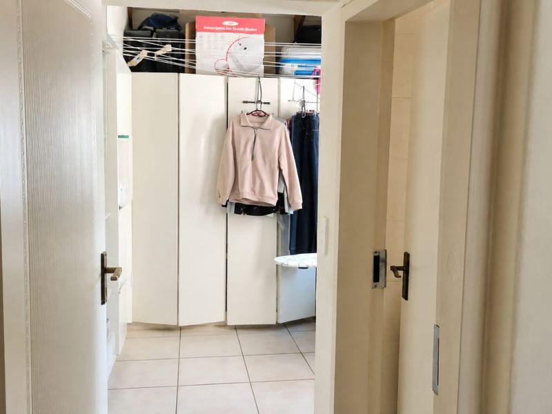 A functional utility space or walk-in storage area featuring built-in cabinetry and tiled flooring, providing practical storage solutions.