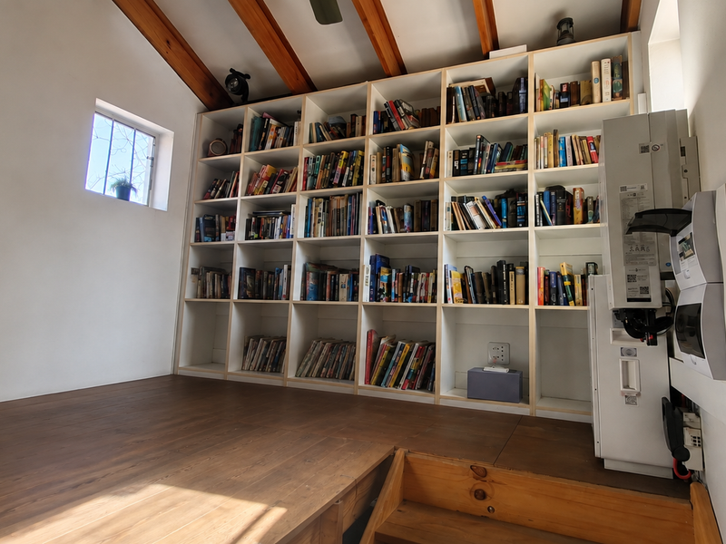 A functional home office or study area featuring extensive built-in shelving, exposed timber ceiling beams, and integrated electrical infrastructure.