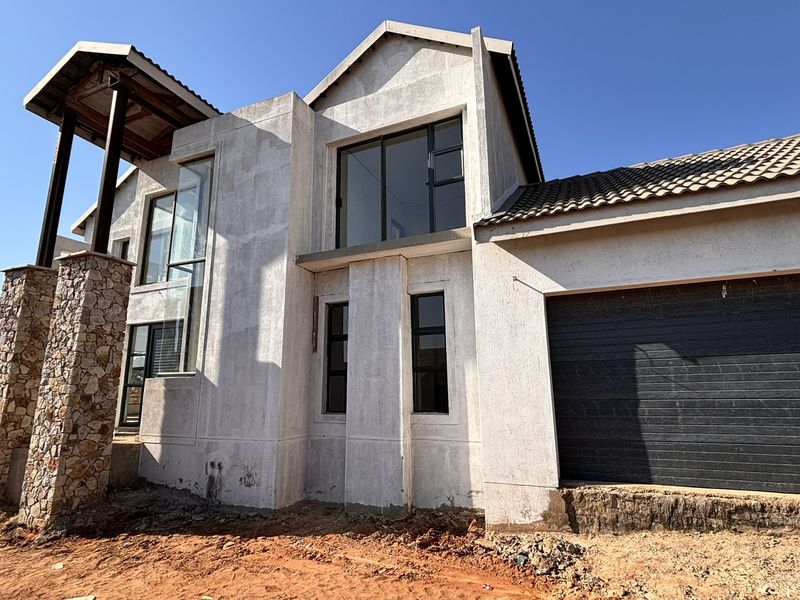 Front elevation of a modern double-storey house under construction, featuring stone-clad pillars, a tiled roof, and a large sectional garage door.