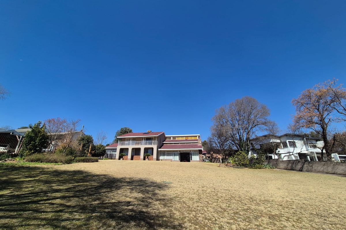A wide-angle view of the rear elevation of a two-story house featuring a balcony, brick detailing, and a large, well-maintained lawn.