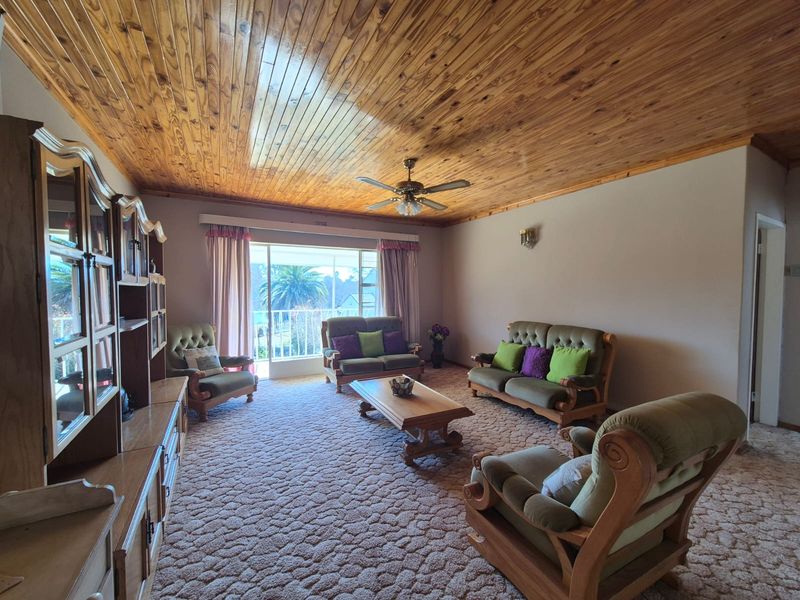 Spacious living room featuring a warm timber tongue and groove ceiling, ceiling fan, and sliding glass door access to an outdoor area.
