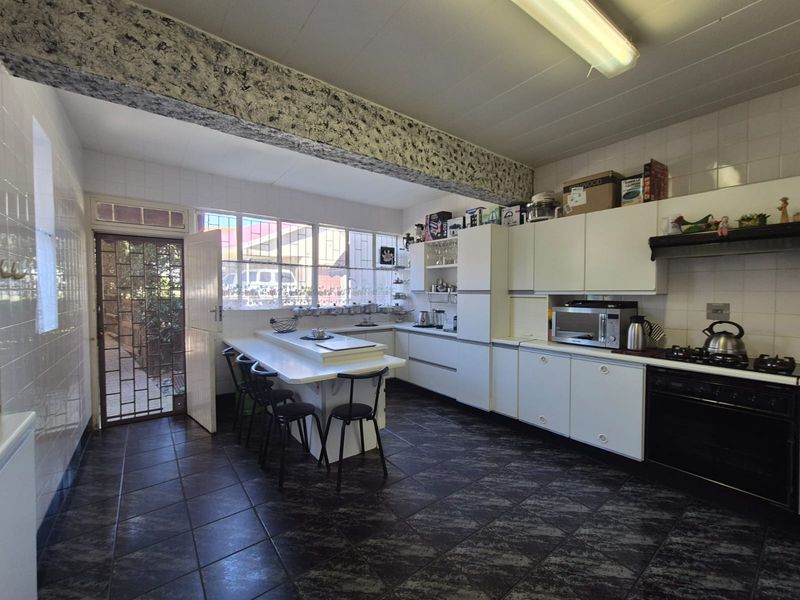 A functional kitchen featuring built-in cabinetry, a gas hob, oven, and tiled finishes, offering a practical layout with direct access to the exterior.