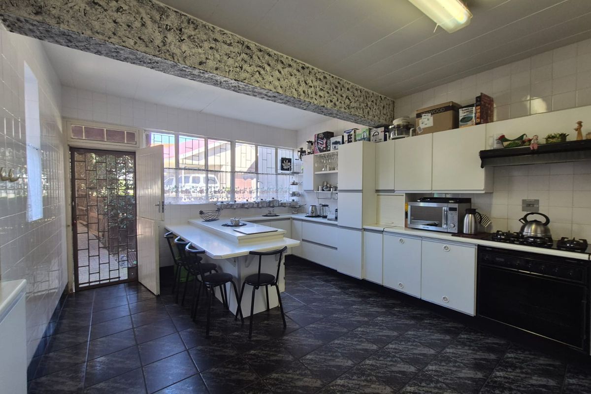 A functional kitchen featuring built-in cabinetry, a gas hob, oven, and tiled finishes, offering a practical layout with direct access to the exterior.