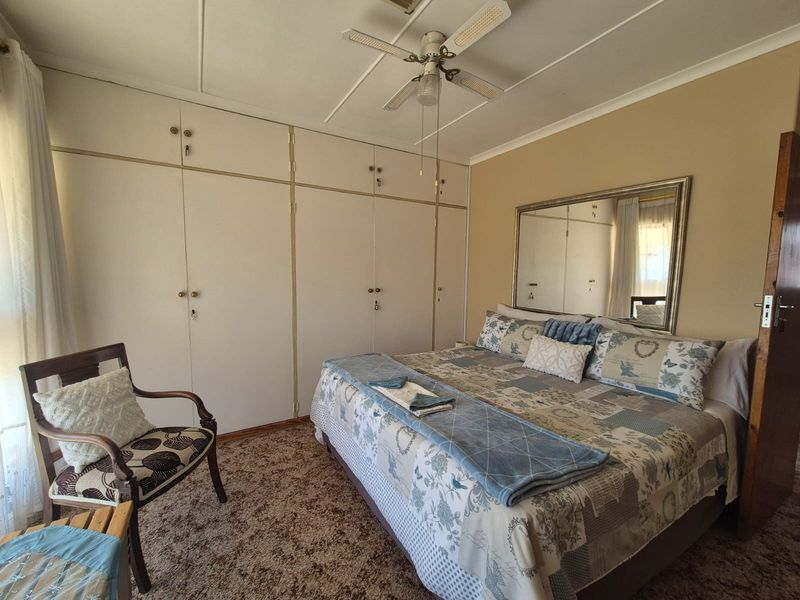 A bedroom featuring built-in cupboards, a ceiling fan, and carpeted flooring, offering a functional space with potential for modernization.