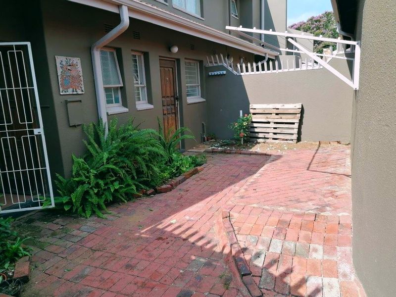 A private rear courtyard featuring brick paving, a security gate, and a wall-mounted washing line, offering a functional outdoor space for the townhouse.