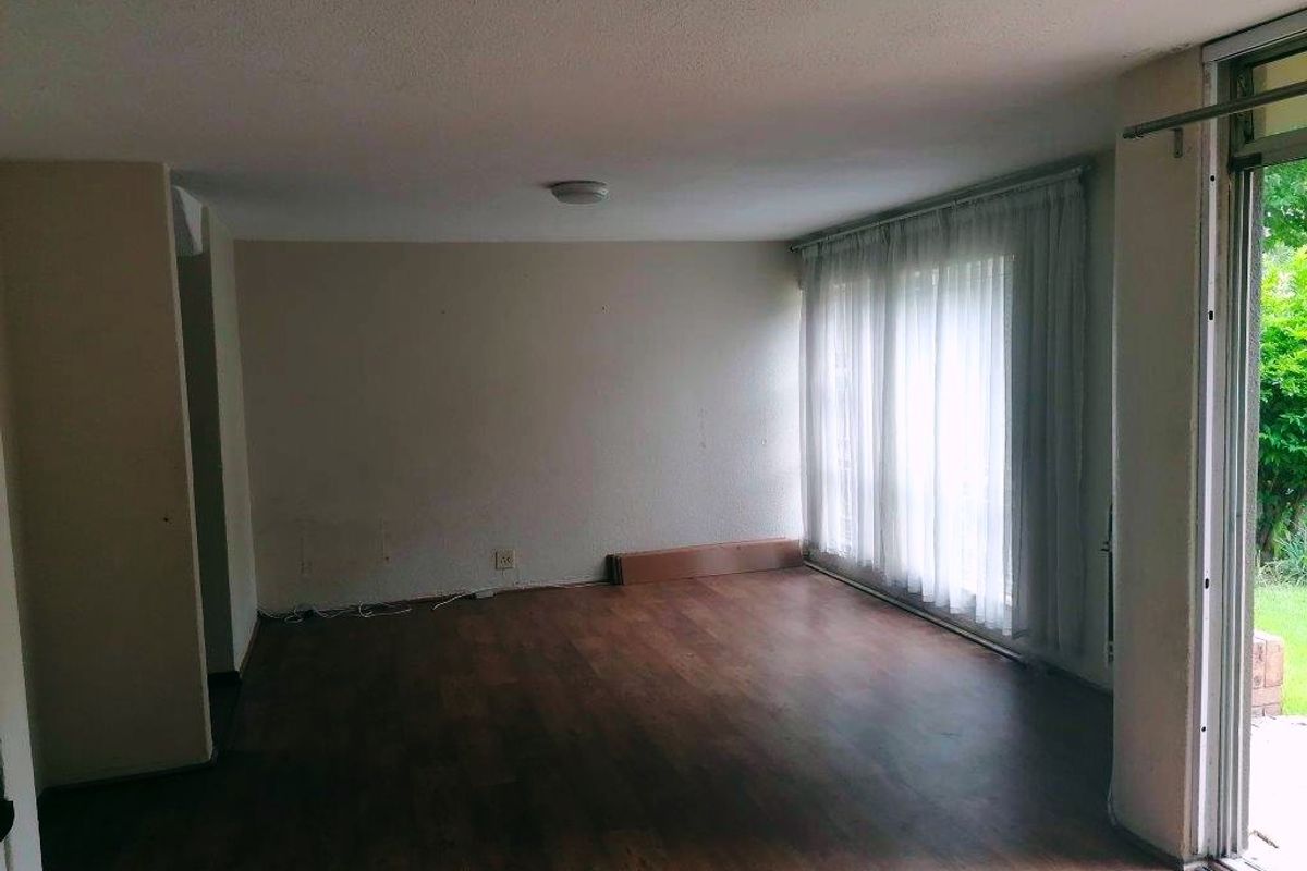 An empty living room featuring laminate flooring and a large sliding glass door providing access to the garden area.