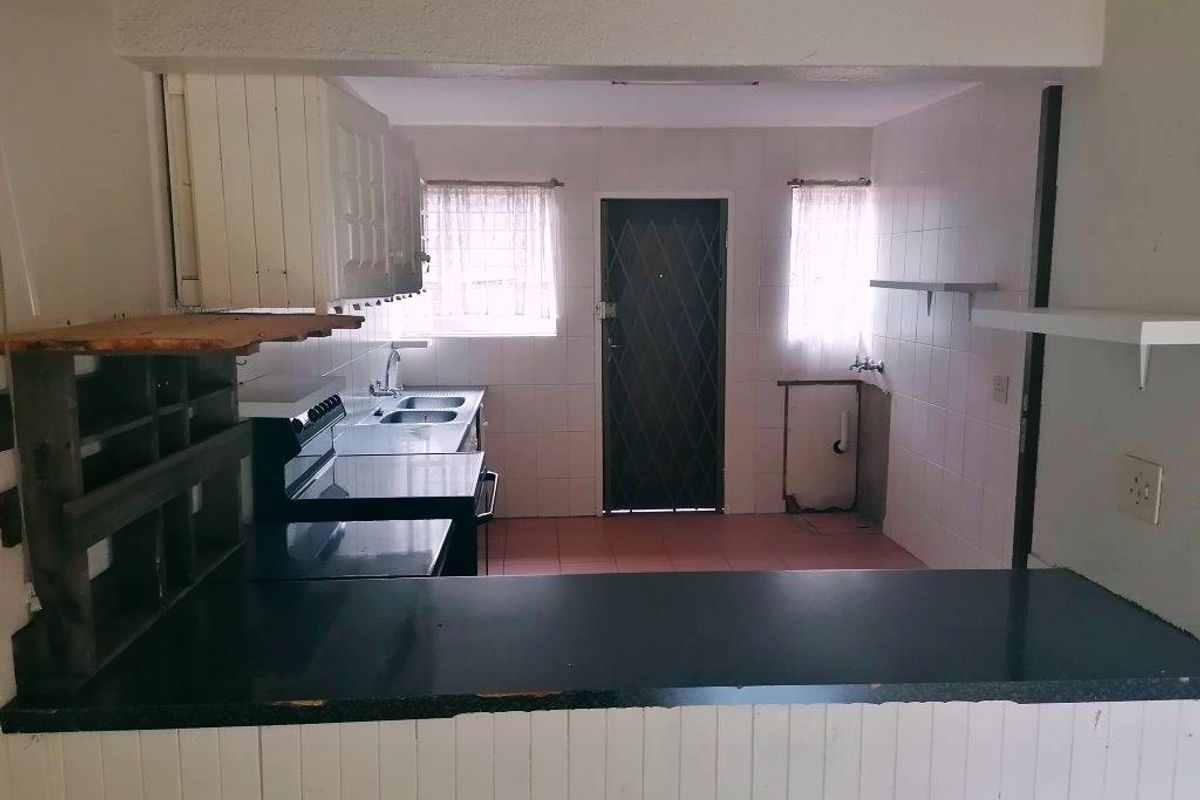 A dated kitchen featuring tiled walls, built-in cabinetry, and a breakfast bar, offering a functional layout ready for modernization and renovation.