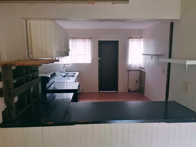 A dated kitchen featuring tiled walls, built-in cabinetry, and a breakfast bar, offering a functional layout ready for modernization and renovation.