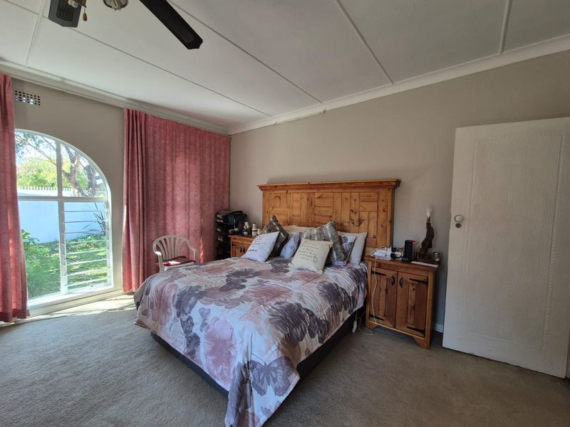 Spacious bedroom featuring a large arched window with security bars, neutral wall tones, and carpet flooring.