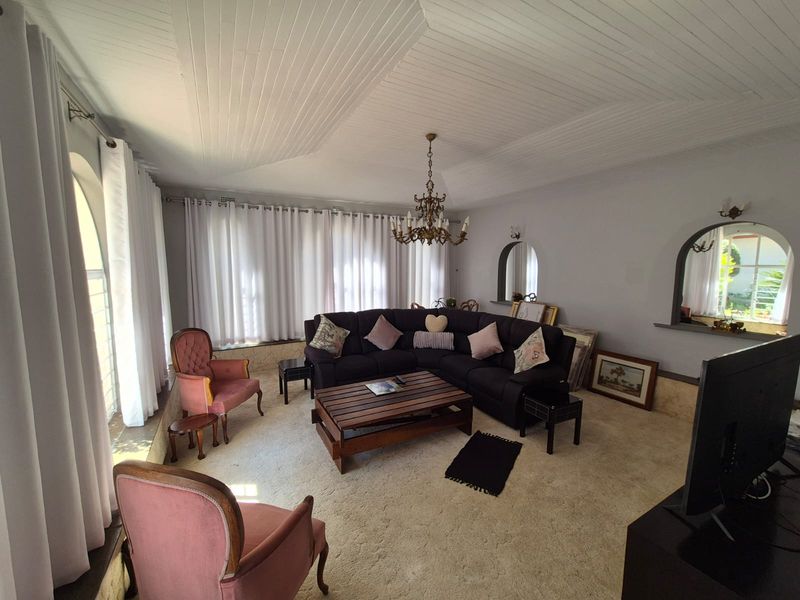 A spacious living room featuring a unique tongue and groove ceiling, arched wall niches, and large windows with natural light.