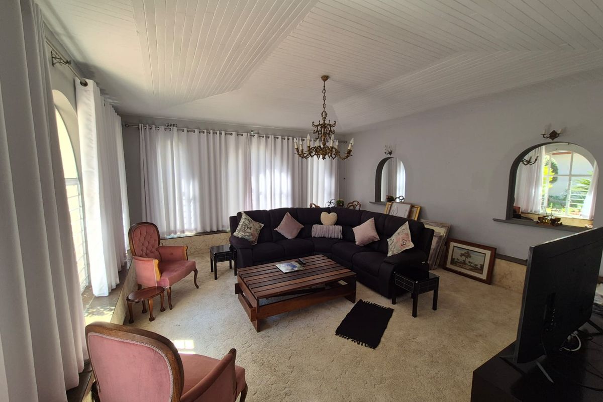 A spacious living room featuring a unique tongue and groove ceiling, arched wall niches, and large windows with natural light.