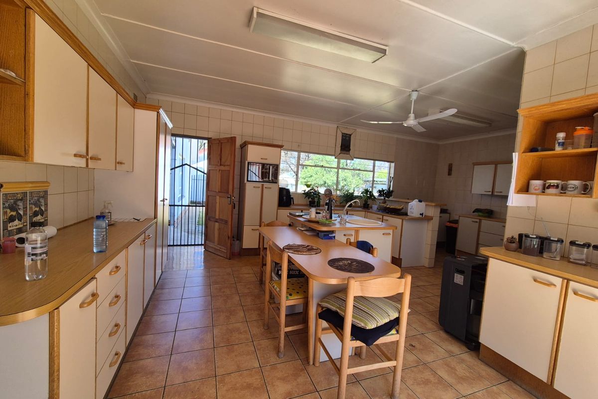 Spacious kitchen featuring ample built-in cabinetry, laminate countertops, tiled flooring, and a functional layout with a central island and direct exterior access.