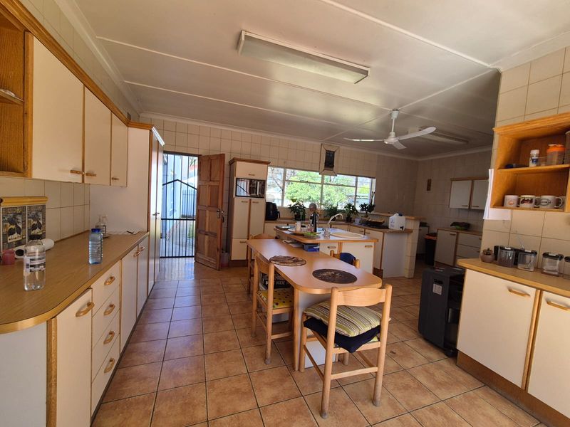 Spacious kitchen featuring ample built-in cabinetry, laminate countertops, tiled flooring, and a functional layout with a central island and direct exterior access.