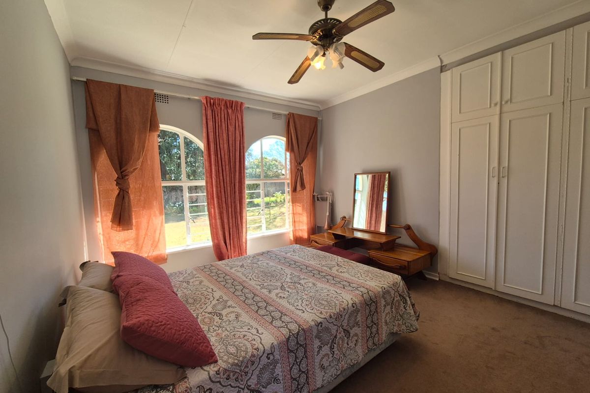 A bedroom featuring built-in wardrobes, a ceiling fan, and arched windows that provide natural light.