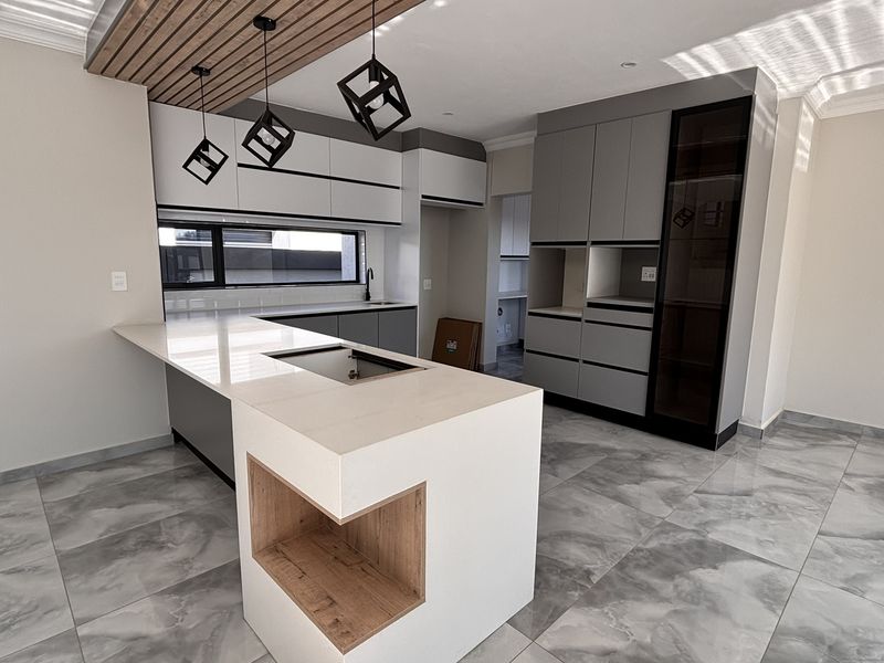 Modern kitchen featuring a central island with quartz countertops, sleek grey cabinetry, timber slat ceiling accents, and high-quality porcelain floor tiles.