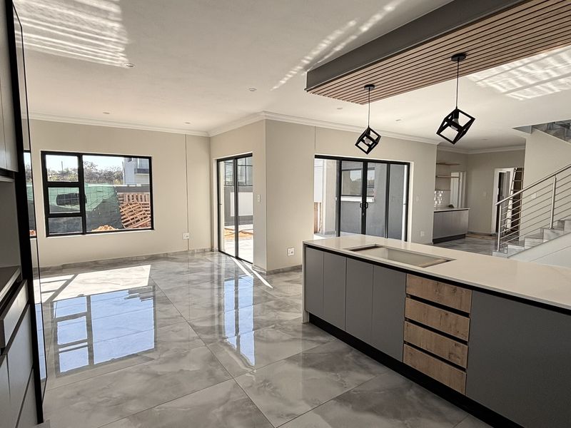 Modern open-plan living and kitchen area featuring high-end finishes, a large island, sleek cabinetry, and a striking slatted timber ceiling detail.
