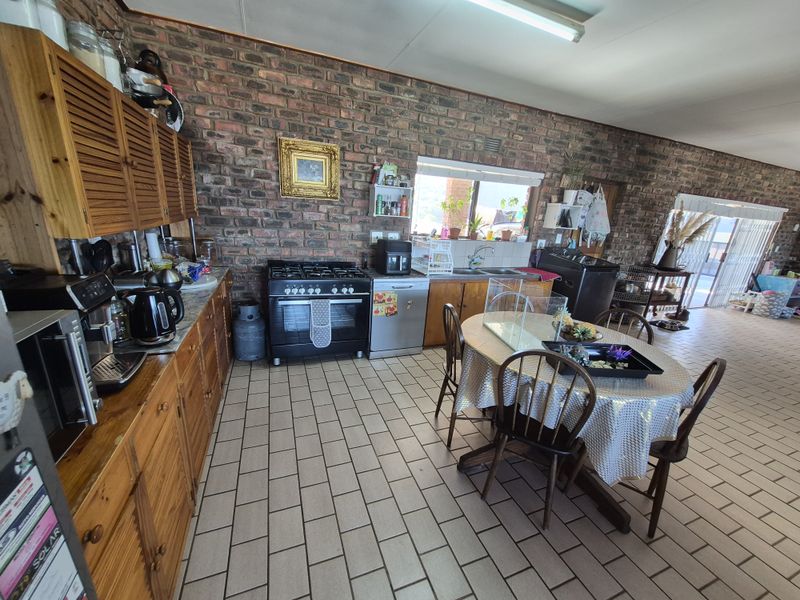 Spacious kitchen featuring exposed brick walls, wooden cabinetry, gas stove, and tiled flooring, offering a rustic aesthetic with potential for modern updates.