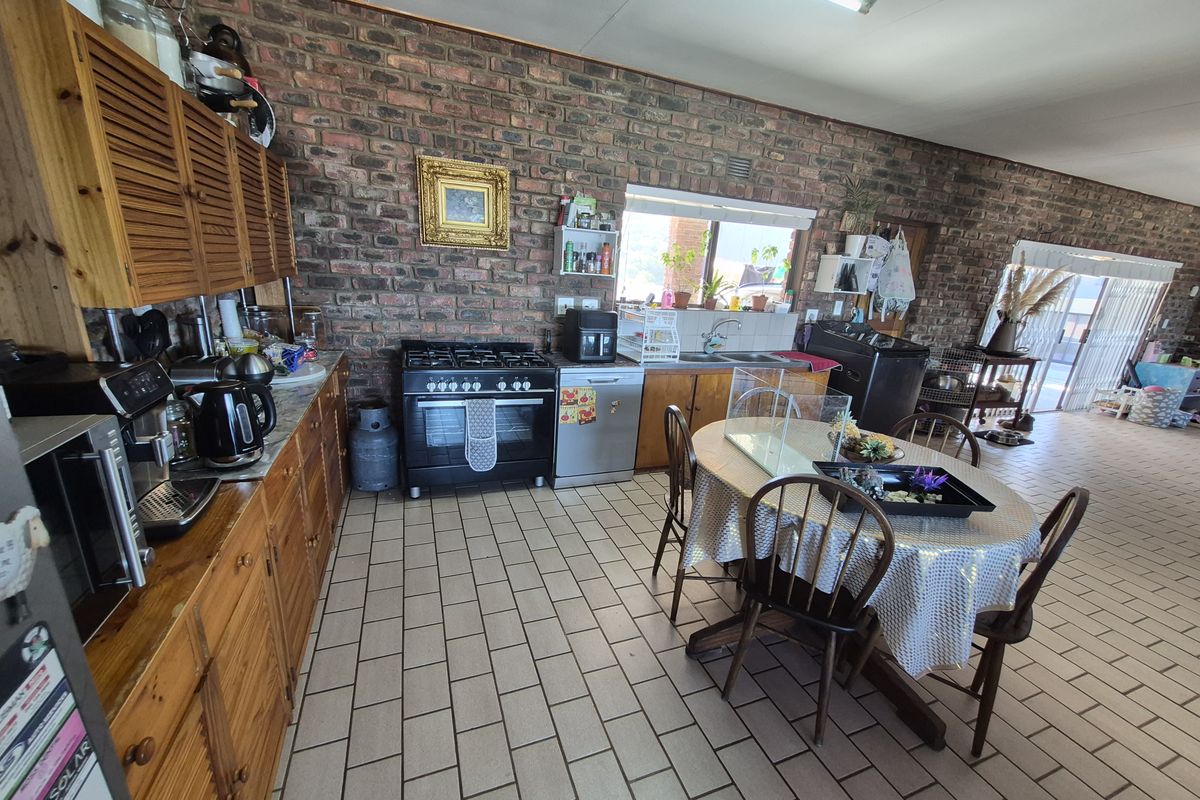 Spacious kitchen featuring exposed brick walls, wooden cabinetry, gas stove, and tiled flooring, offering a rustic aesthetic with potential for modern updates.