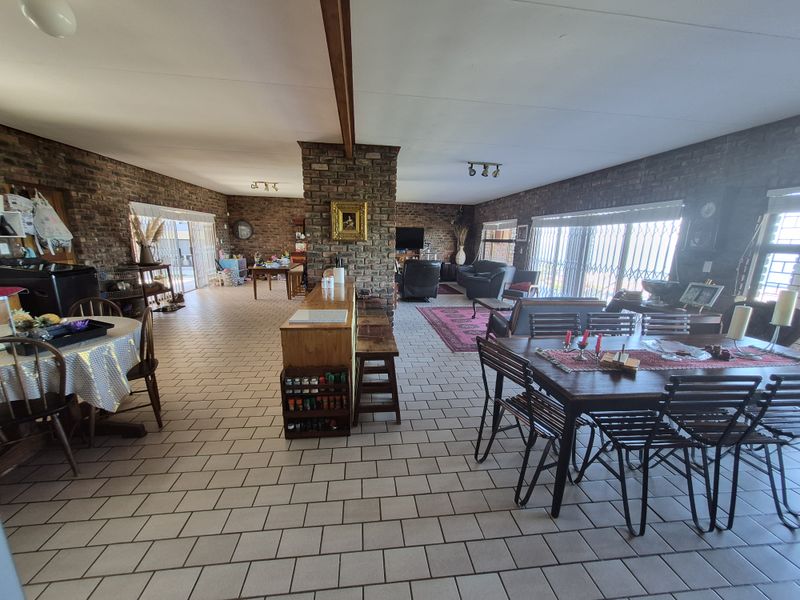 Spacious open-plan living and dining area featuring exposed brick walls, tiled flooring, and a central brick pillar, offering a versatile layout for family living.