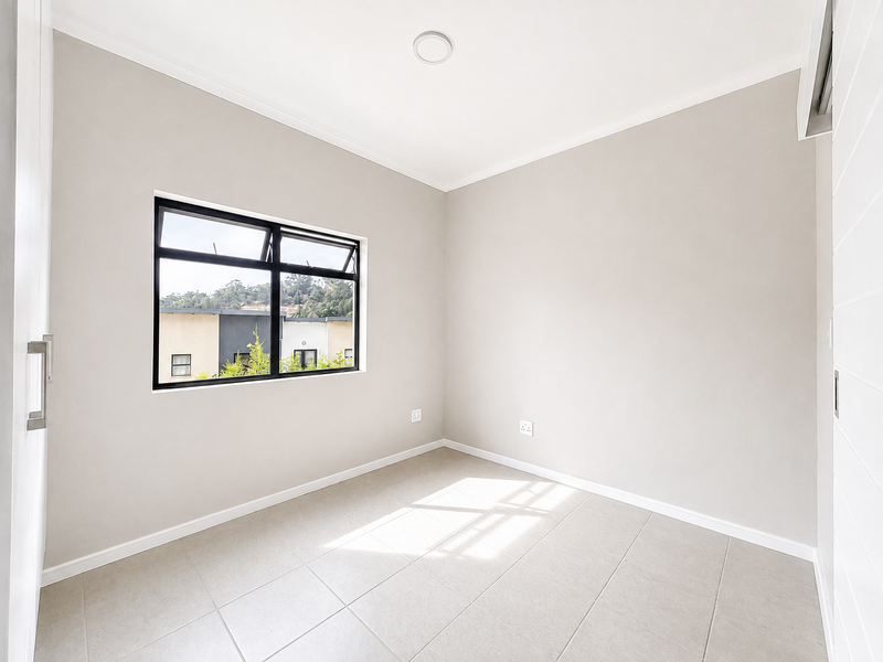 A bright, empty bedroom featuring neutral wall tones, tiled flooring, and a built-in cupboard, offering a clean and versatile space.