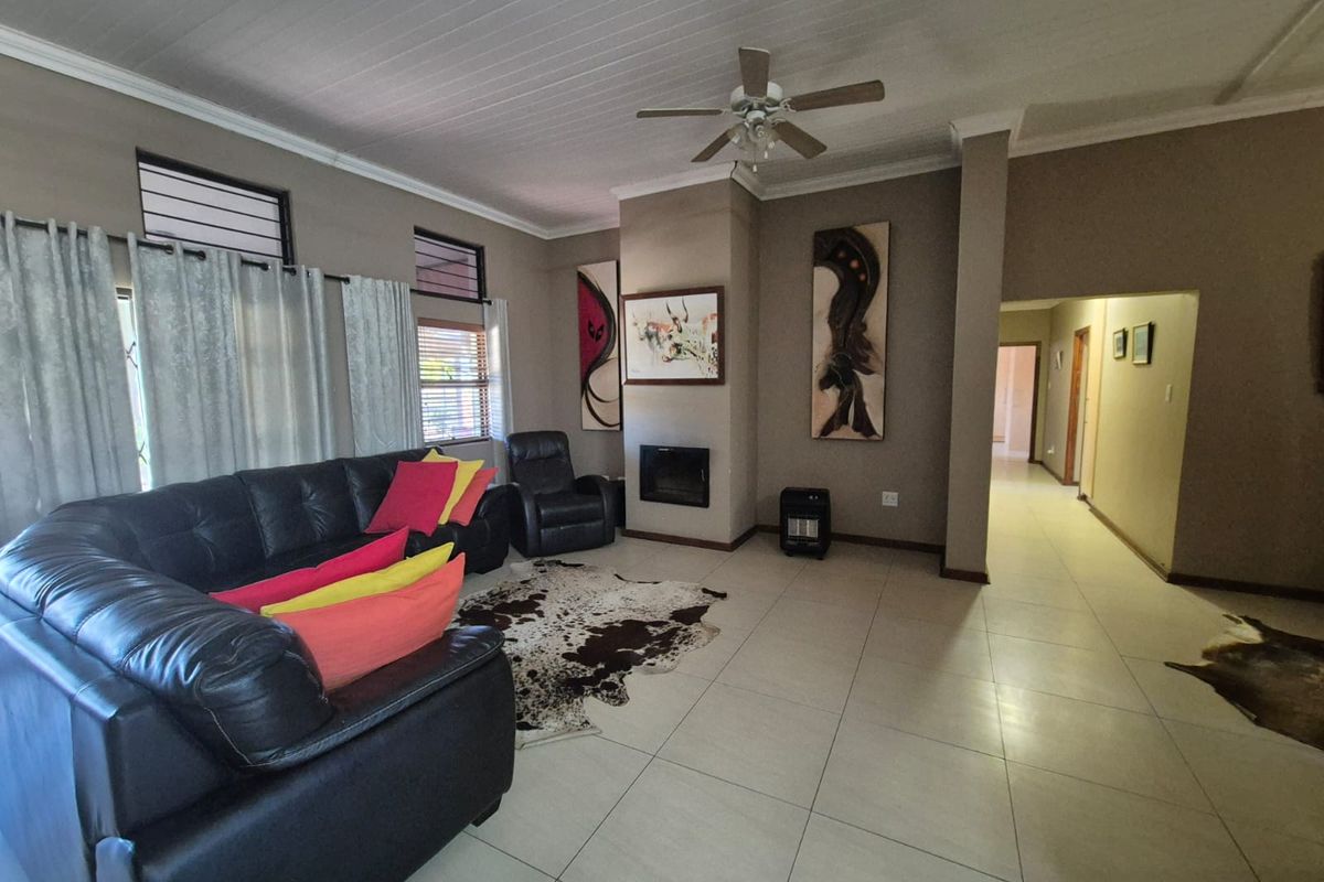 Spacious living room featuring tiled flooring, a built-in fireplace, and a ceiling fan, providing a comfortable and functional family area.