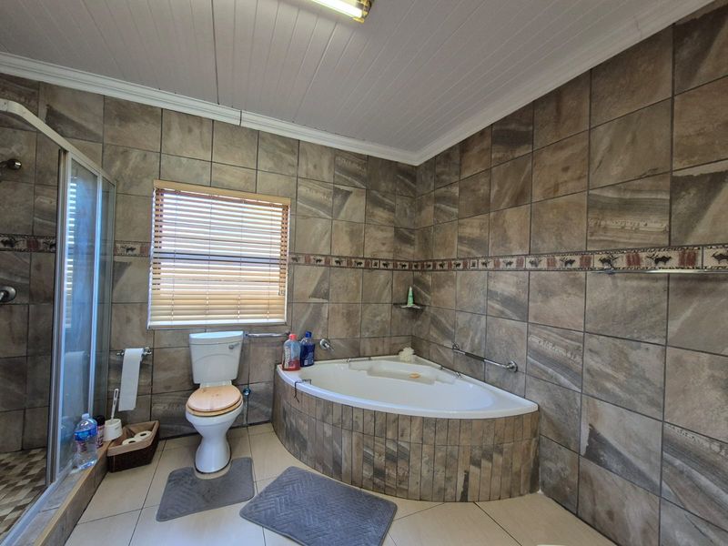 A functional bathroom featuring a corner bathtub, a separate glass-enclosed shower, and full-height wall tiling.