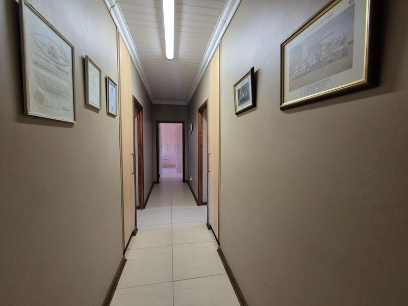 A functional hallway featuring tiled flooring, built-in storage cupboards, and neutral wall finishes, providing access to multiple rooms within the home.
