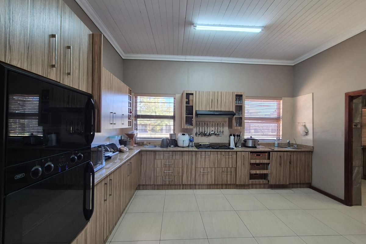 Spacious kitchen featuring wood-grain cabinetry, built-in oven, hob, extractor fan, and tiled flooring with ample counter space.